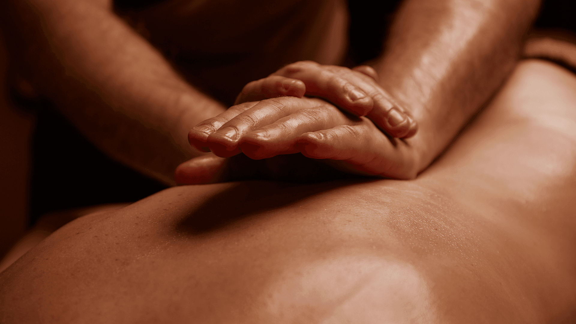 Therapist gliding oiled hands along a guest's back during a Swedish massage